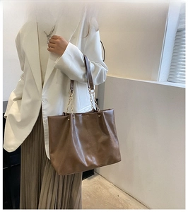 Détail d'un sac cabas marron avec chaîne dorée et coutures verticales décoratives