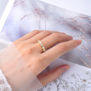 Close-up of S925 sterling silver ring with five round moissanite stones on finger