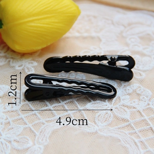 Detail view of black metal hair clips measuring 1.2cm by 4.9cm on lace background