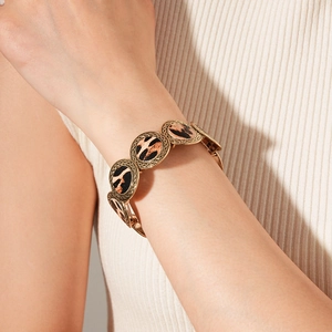 Close-up of leopard print round panels with gold embossed metal frame on wrist