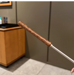 Detailed close-up of a dark wooden handle and steel spring on a manual whisk tool