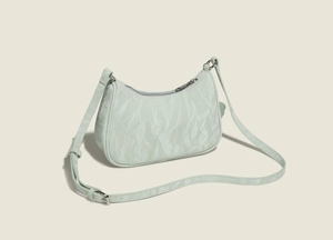 Close-up of light green pleated texture on a stylish underarm bag with adjustable strap