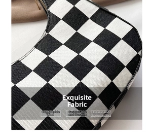Close-up of black and white checkerboard knit fabric and metal zipper detail on baguette bag