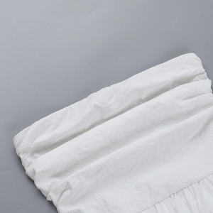 Gros plan du tissu blanc d'une robe montrant la texture plissée naturelle en coton