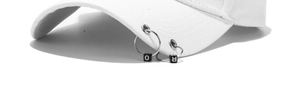 Detail of white baseball cap brim featuring silver metal rings and O and R letter beads