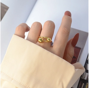 Detail of minimalist 18K gold plated ring with two metal beads on a female hand
