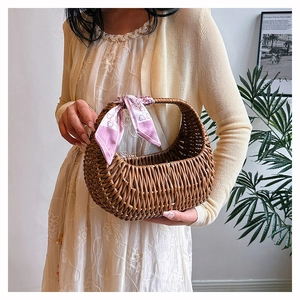 Brown woven rattan basket handbag detail with a decorative pink silk scarf on handle