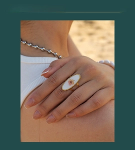 Detail of vintage gold flower ring featuring pink dried blossoms on a model's hand