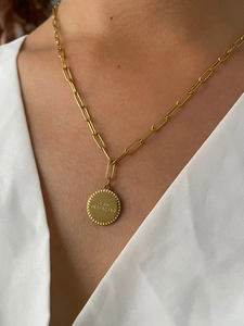 Gros plan d'un collier en titane or 18 carats avec pendentif gravé sur une femme