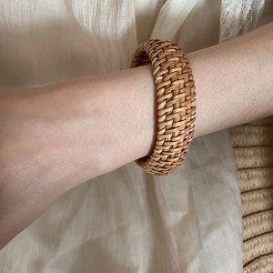 Gros plan d'un bracelet en rotin tressé à la main au poignet, style bohème naturel