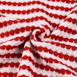 Gros plan détaillé du tissu en maille rayé rouge et blanc montrant la texture et les plis