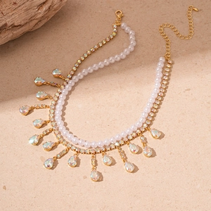 Detail of double-layer gold necklace featuring pearls and pear-shaped colorful zircon drops