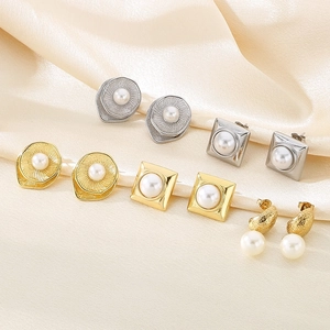Detail of diverse matte gold and silver geometric titanium earrings with white pearls