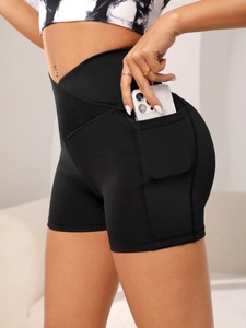 Detail of high-waisted yoga shorts featuring a side pocket for phone and cross waist design