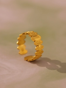Dettaglio macro dell'anello dorato aperto con rilievo a spiga e placca ovale lucida