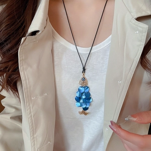 Detail of fish pendant necklace with blue shell scales and evil eye on a model
