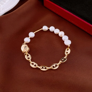 Detailed shot of gold plated bracelet with freshwater pearls on brown silk fabric