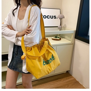 Detail of a bright yellow canvas tote bag with drawstring closure and printed text