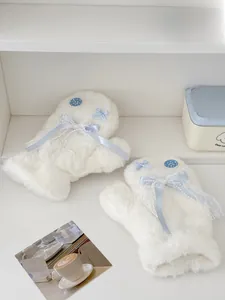 Close-up of white plush gloves with blue silk bow, pearls, and decorative button detail