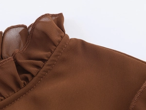 Détail d'une robe en mousseline marron avec encolure à volants et coutures fines