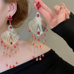 Detail view of vintage red crystal tassel earrings with ornate silver filigree work