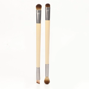 Dual-ended eyeshadow and eyebrow brushes with natural wooden handles on white background