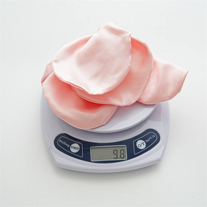 Pink silk floral hair scrunchie shown on a digital scale weighing exactly 9.8 grams