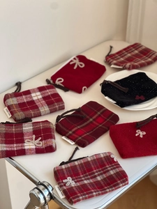 Detail of red wool plaid pouches with bows and 'simple wish' labels on white surface