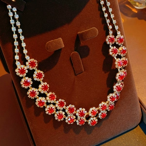 Close-up of a double-layer necklace with red round gemstones and clear diamonds on a velvet stand