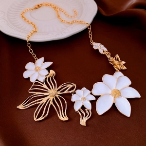 Macro view of gold and white floral enamel earrings on a silk brown background