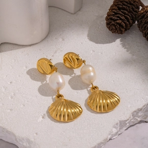 Elegant 18K gold-plated shell pendant earrings with freshwater pearls on stone surface