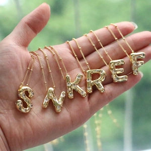 Detail of 18k gold bubble letter pendants with cubic zirconia on satellite chains