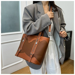 Detail of vintage brown patchwork tote bag showing pebbled texture and buckle straps