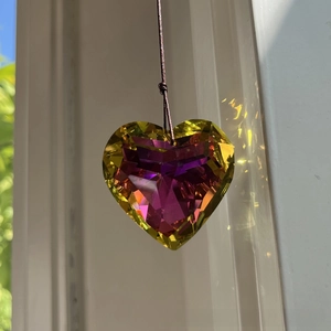 Macro shot of 45mm faceted heart crystal suncatcher creating colorful light reflections
