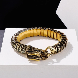 Detail of golden dragon scale bracelet featuring a carved dragon head clasp on white podium