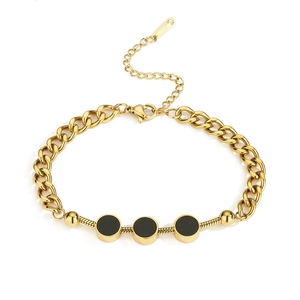 Detail of gold Cuban and snake chain bracelet with black enamel circular inserts