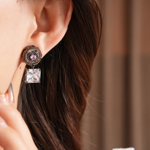 Close-up of vintage flower earrings with pink stone and square zircon on model