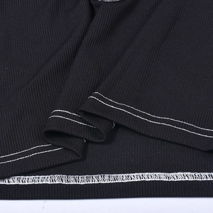 Makro-Detail des schwarzen Rippstrickgewebes und der weißen Doppelnadelstiche am Top