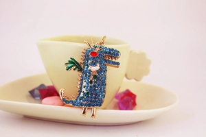 Détail du porte-clés crocodile en cristal bleu avec cadre doré et ailes vertes