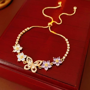 Detail eines verstellbaren Goldarmbands mit Blumen, Schmetterling und lila Zirkon