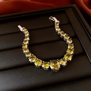 Macro shot of yellow-green gemstone bracelet with silver metal base on black velvet