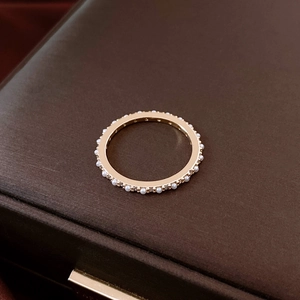 Detalle de anillo bañado en oro de 14K con perlas y pavé sobre un joyero de terciopelo