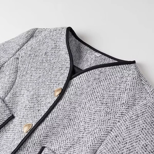 Close-up of gray tweed jacket showing weaving texture and gold heart-shaped buttons