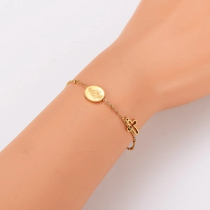Minimalist gold stainless steel bracelet with religious icon and bow pendants on wrist