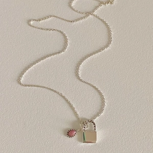 Detail of 925 sterling silver chain with a pink teardrop gem and square lock pendant