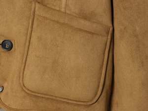 Detail einer braunen Wildlederjacke mit aufgesetzter Tasche und feiner Stoffstruktur