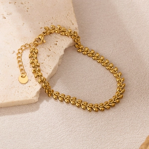 Detail of gold wheat leaf textured bracelet with lobster clasp on cream stone