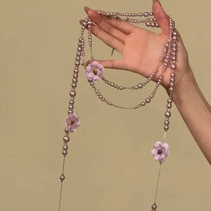 Detaillierte Nahaufnahme einer fliederfarbenen Perlenkette mit lila Stoffblumen