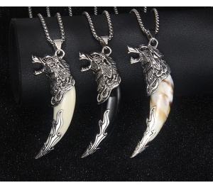 Three variants of wolf tooth necklaces in white black and brown on a black display stand