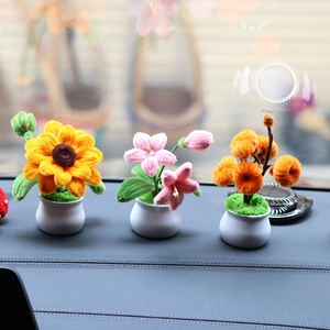Three handmade pipe cleaner flower pots on car dashboard featuring a yellow sunflower